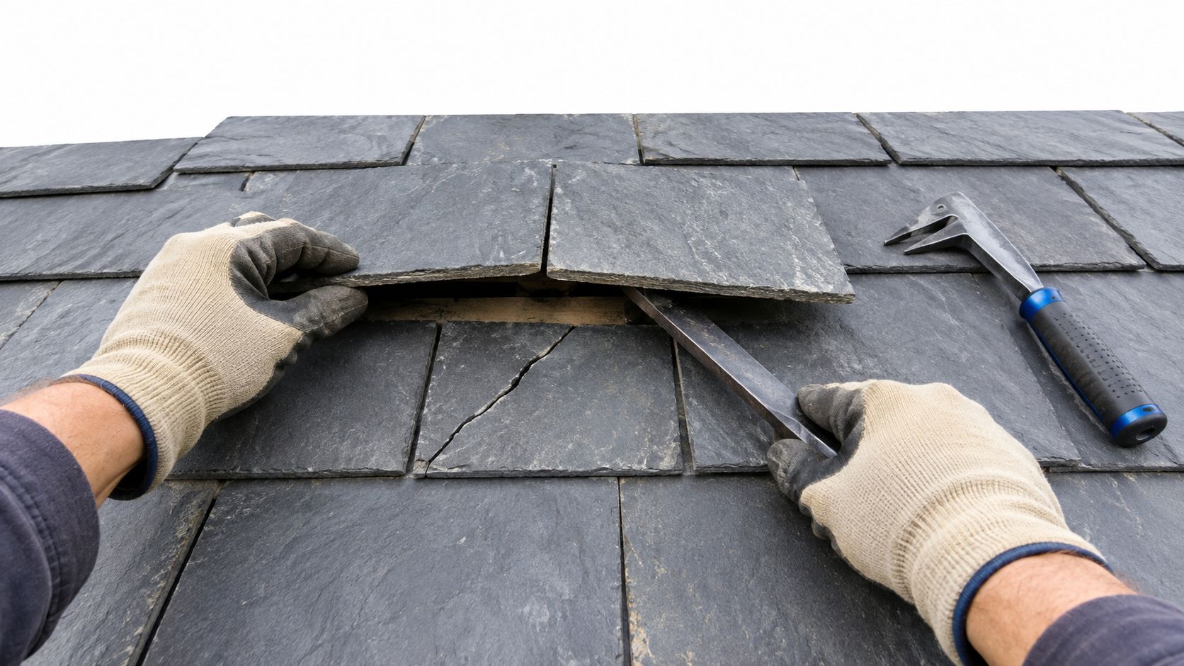 Close up of a construction worker using a metal tool to repair a cracked slate roof tile.